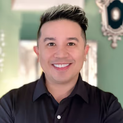 Smiling person in black shirt against soft green background